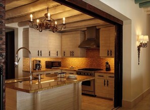 A modern kitchen with a central island, stainless steel appliances, and a hanging light fixture. - Luxury Villa in 5 Star Resort (Cabo San Lucas)