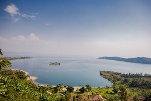 A coastal landscape with a clear view of a large body of water, a small island, and surrounding greenery. - Serene Lake View Lodge in Kayove, Rwanda (Kayove)