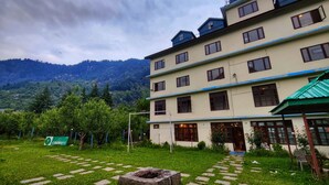 Un hotel de varios pisos con techo plano y toldo verde.