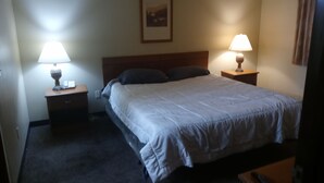 Une chambre d’hôtel avec un lit, deux lampes de chevet, une table de chevet et un tableau encadré au mur.