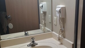 Une salle de bain équipée d’un lavabo, d’un miroir et d’un distributeur de serviettes.