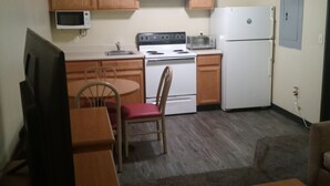Une cuisine compacte dotée de meubles en bois, d’un four à micro-ondes, d’une cuisinière, d’un réfrigérateur et d’un coin repas avec une table et des chaises.