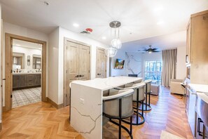 A modern kitchen with a central island, bar stools, and a dining area.
