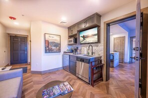A modern kitchen with stainless steel appliances, a flat-screen TV, and a dining area with a wooden table.