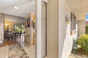 A hotel room with a sliding glass door leading to a balcony, a dining area with a table and chairs, and a view of the outdoors. - Near Coachella | Golf Course, Community Pool & Tennis Courts | Resort Lifestyle (Palm Desert)