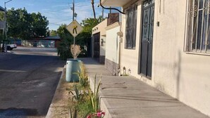 Une rue résidentielle avec un trottoir, un panneau de passage piéton et un immeuble dont les fenêtres sont protégées par des barreaux.