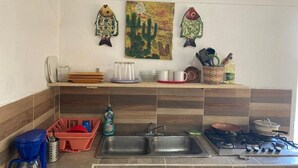 Une cuisine équipée de deux éviers, d’une machine à café, d’un égouttoir et d’une cuisinière.