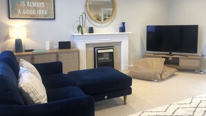 A living room with a blue sofa, a fireplace, a television, and a framed quote on the wall.
