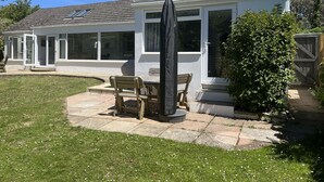 A house with a patio, a covered table, and a large umbrella.