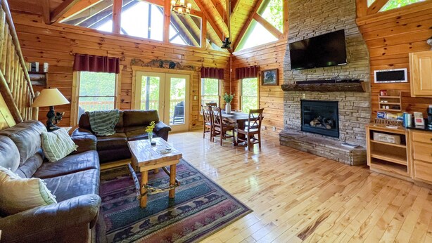 Une cabane spacieuse avec un plafond haut, des murs en bois, une cheminée et un coin repas.
