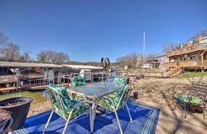 An outdoor patio with a table and chairs, a dock with boats, and a wooden deck with a railing. - Private Dock, Waterfront Views! Sunrise Beach Home (Sunrise Beach)