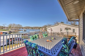 A deck with a table and chairs, overlooking a lake and a house. - Private Dock, Waterfront Views! Sunrise Beach Home (Sunrise Beach)