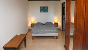 A bedroom with a bed, bedside lamps, a bench, and a wooden wardrobe.