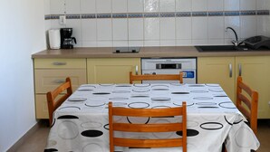 A compact kitchen with a dining table set for four, a coffee maker, and a sink.