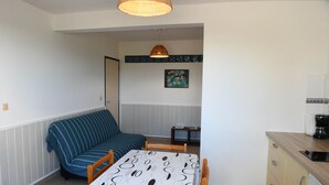 A compact living space with a dining table, a sofa, a small kitchen area, and a decorative wall piece.