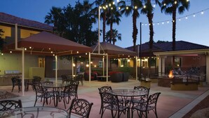 An outdoor patio area with tables and chairs, string lights, and a barbecue grill. - Marriott Desert Springs I Studio (Palm Desert)