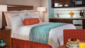 A hotel room with a bed, bedside table, lamp, and a breakfast table with fruit and juice. - Marriott Desert Springs I Studio (Palm Desert)