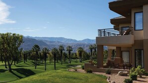 A modern two-story building with a balcony, surrounded by a well-maintained lawn and palm trees, overlooking a mountainous landscape. - Marriott Desert Springs I Studio (Palm Desert)