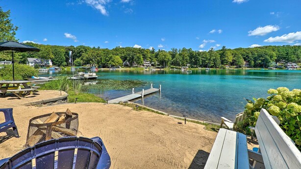 A lakeside view with a dock, picnic tables, and a fire pit. - Lakefront Newaygo Home - Private Dock, Kayaks (Newaygo)