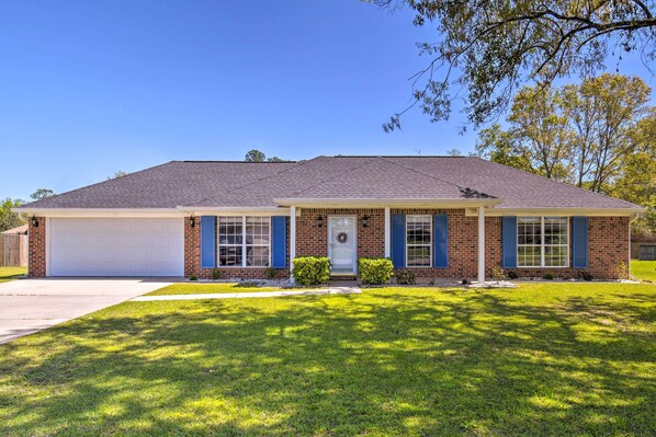 A two-story house with a garage, a front porch, and a well-maintained lawn. - Foley Getaway w/ Fenced Yard - 13 Mi to Beaches! (Foley)
