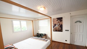 Ein Schlafzimmer mit Bett, Fenster, Tür und einem Gemälde an der Wand.