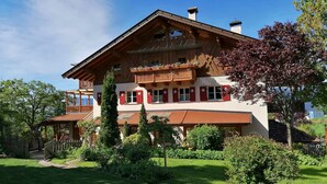 Une grande maison en bois dotée de nombreux balcons et d’un jardin bien entretenu.
