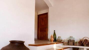 Una escalera que lleva a una puerta, un jarrón grande y varios recipientes en una estantería.