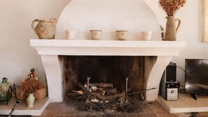 A fireplace with a white mantel, logs, and a shelf with decorative items. - Sunny holiday home in Provence with pool (Séguret)