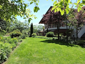 Un jardin bien entretenu, avec une pelouse, divers arbustes et un bâtiment au style architectural traditionnel.