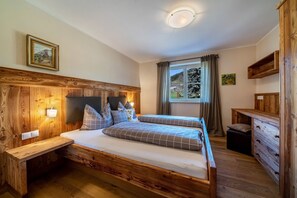 Un lit en bois avec une tête de lit, des tables de chevet, une commode et une fenêtre avec des rideaux.