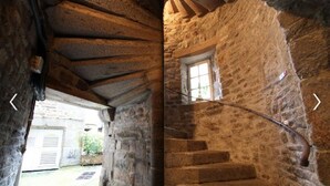 A stone staircase with a window, leading to an outdoor area with a door and a small garden. - In the heart of the city Gîte "La cour des trois rois" (The court of the three kings) (Villedieu-les-Poêles-Rouffigny)