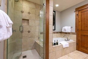 Ein modernes Badezimmer mit einer gläsernen Duschkabine, einem Waschbecken mit Toilettenartikeln und einer Holztür.