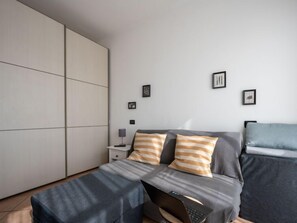 Un dormitorio moderno con una cama, un escritorio y una computadora portátil.