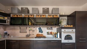 Une cuisine moderne avec des meubles de couleur sombre, un four encastré et un plan de travail sur lequel sont disposés divers ustensiles de cuisine.