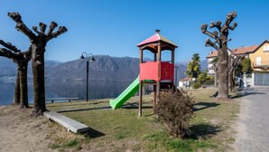 Un terrain de jeux avec un toboggan et un petit kiosque, entouré d’arbres et offrant une vue sur les montagnes.