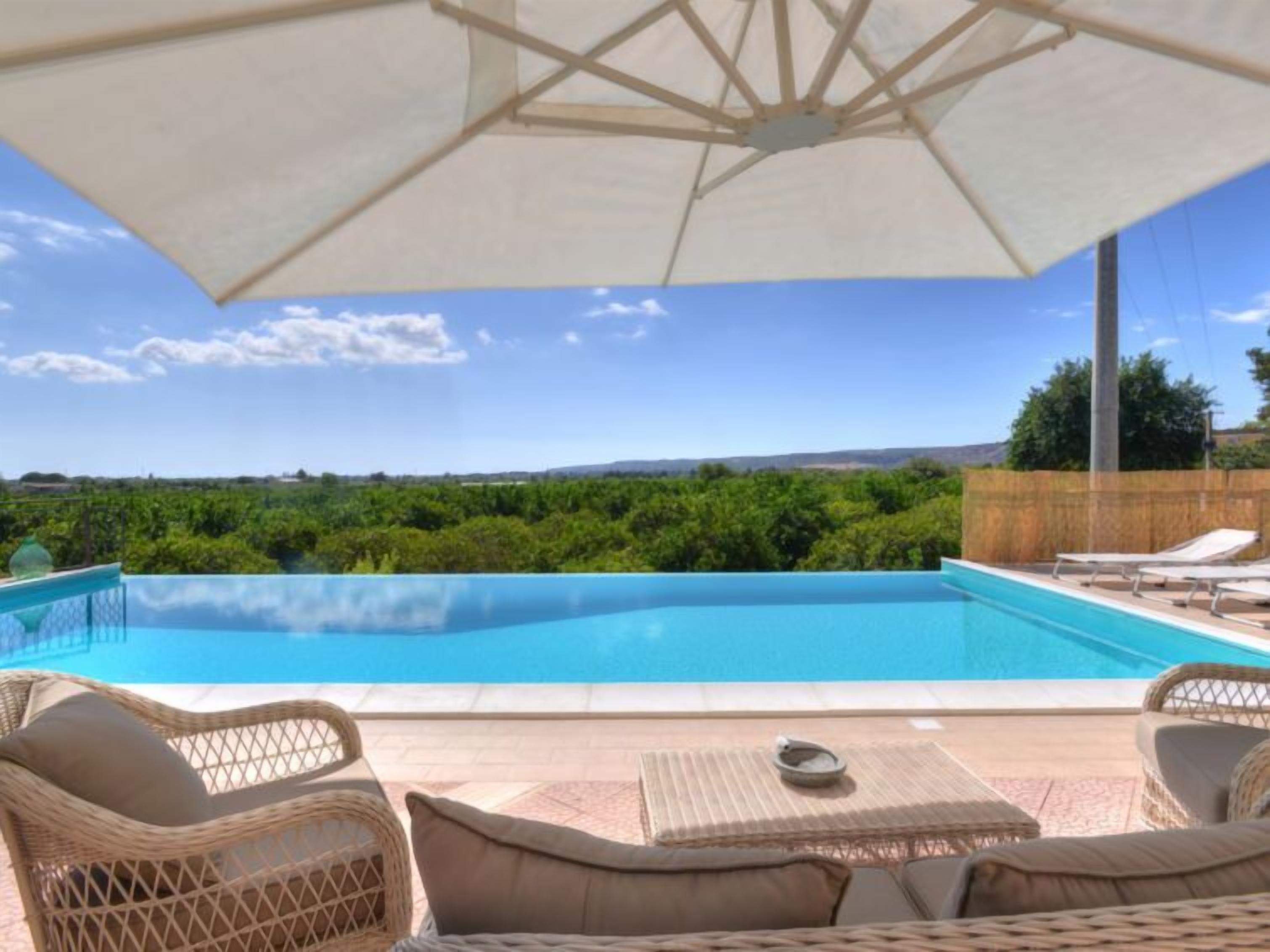 A swimming pool with lounge chairs and an umbrella.