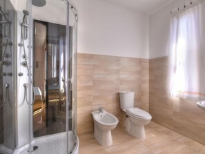 Ein modernes Badezimmer mit einer Duschkabine, einem Bidet und einer Toilette.