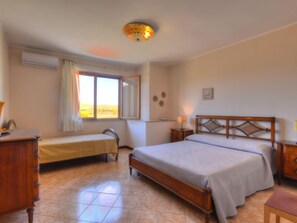 Ein Schlafzimmer mit Bett, Schreibtisch, Stuhl, Fenster und Deckenleuchte.