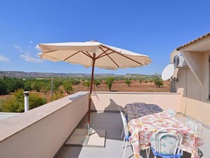 Eine Terrasse mit Tisch, Stühlen, einem Sonnenschirm und Blick auf die Landschaft.