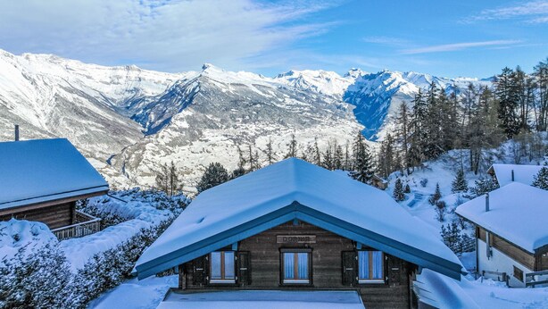 A wooden cabin with a sloped roof, surrounded by snow-covered trees and mountains. - Vacation home Dorine by Interhome (Nendaz)
