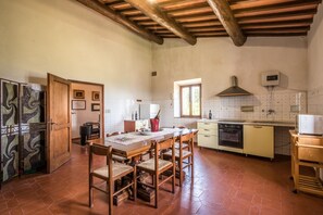 A kitchen with a wooden table, chairs, a stove, and a window.