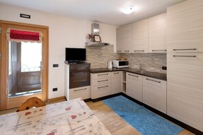 Una cucina moderna con mobili in legno, un forno a microonde e una televisione.