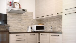 A kitchen with a microwave, oven, and a clock on the wall.