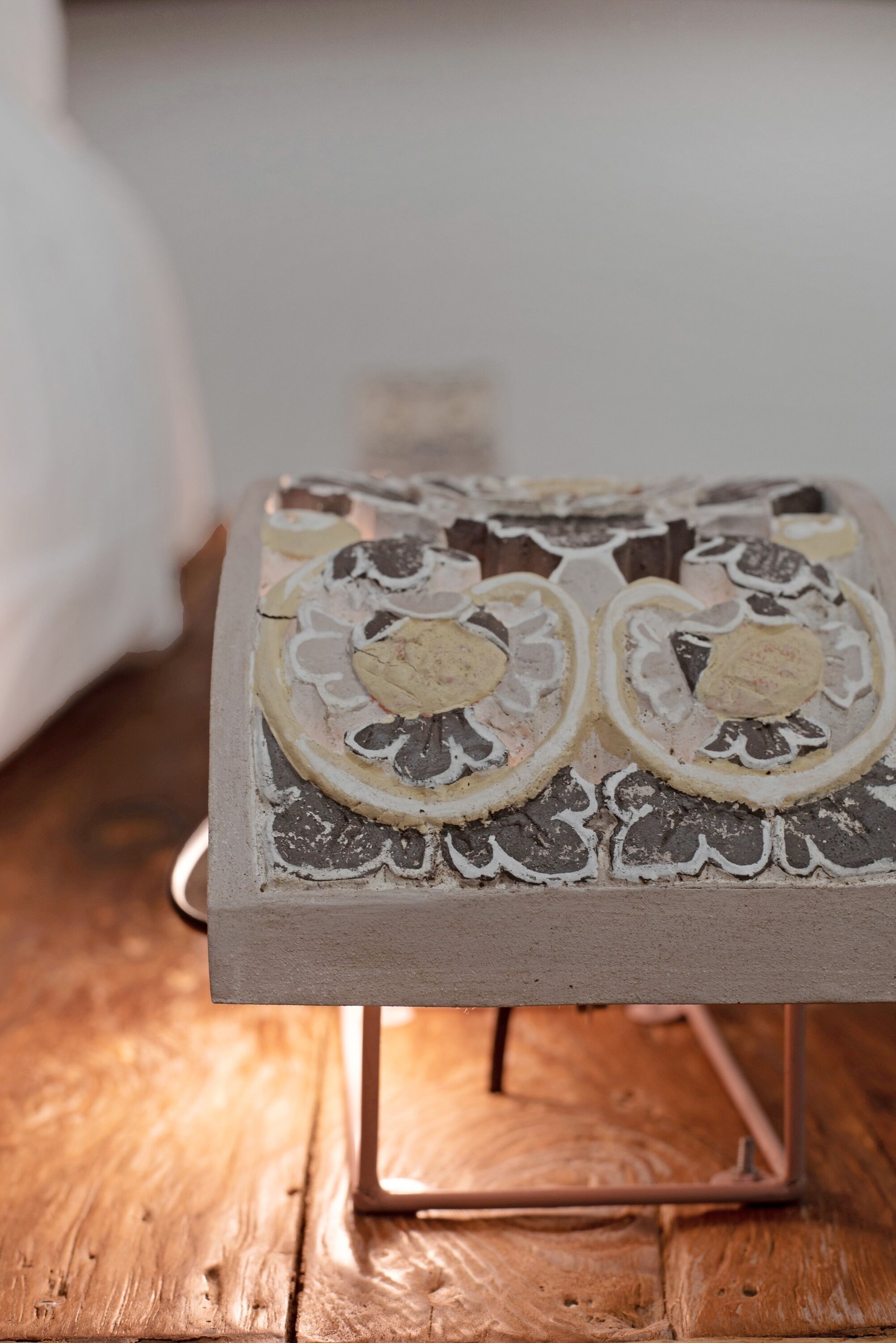 A square table with a decorative design, placed on a wooden floor.