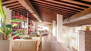 An interior with a wooden ceiling, a sofa, a bookshelf, and a potted plant. - Incredible Villa in the Heart of Tuscany (Cecina)