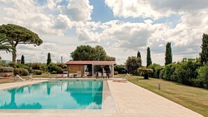 A swimming pool with lounge chairs, a covered seating area, and surrounding greenery. - Incredible Villa in the Heart of Tuscany (Cecina)