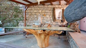 Una pared de piedra rústica, una mesa de madera con cubierta de vidrio y una cuerda.