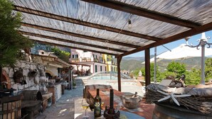 Un patio exterior con muebles rústicos, una botella de vino y una mesa de piedra con la inscripción 'Villa Verde'.