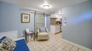 Un espacio habitable compacto con kitchenette, un sofá, una pequeña mesa y una silla.