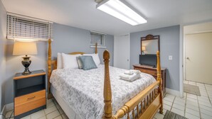 Un dormitorio con cama, mesitas de noche, lámpara, espejo y televisor.